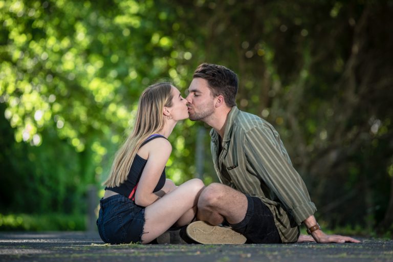 Portrait of young couple sitting and kissing by Katja Photography