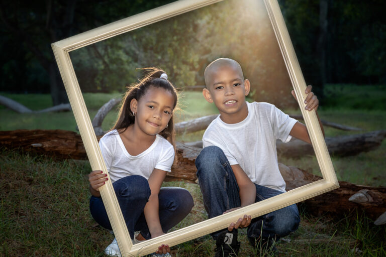 Portrait of a young brother and sister holding a picture frame by Katja Photography