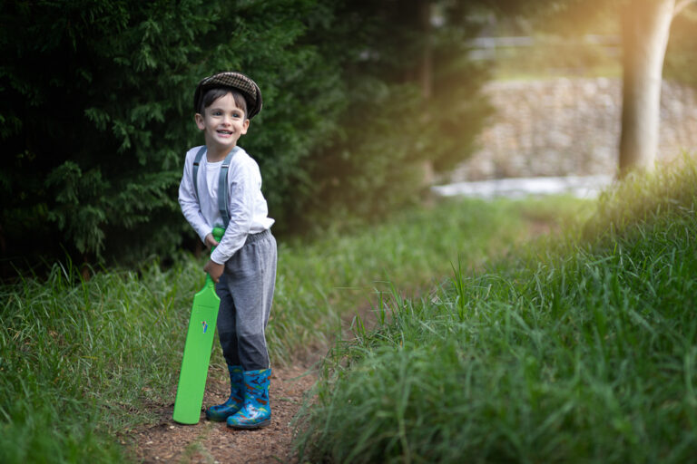 Portrait of a young boy standing with a cricket bat by Katja Photography