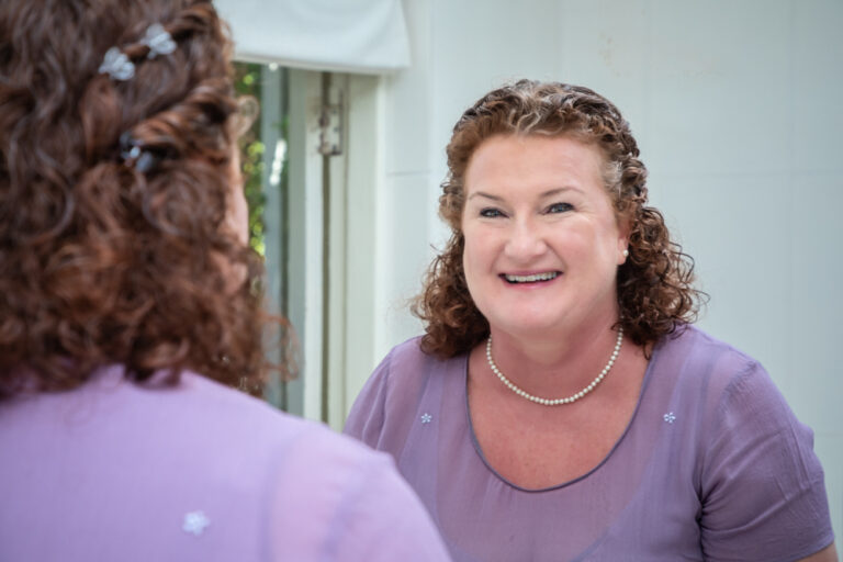 Woman smiling into the mirror by Katja Photography