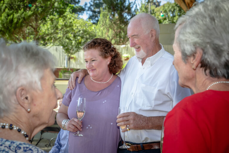 Father with his arm around his adult daughter at a family celebration by Katja Photography