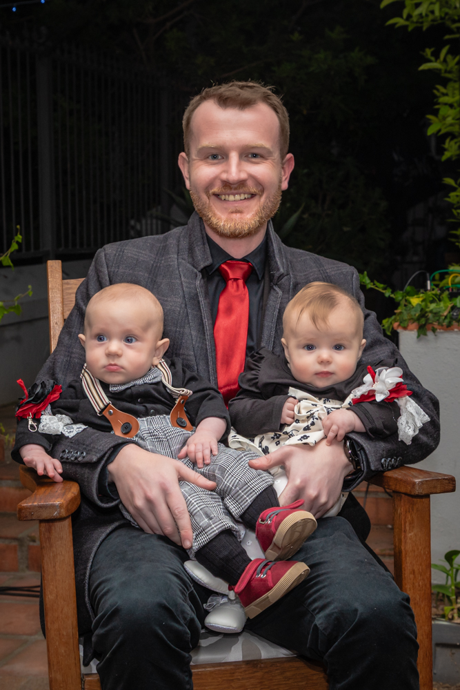 Man holding baby twins on his lap by Katja Photography