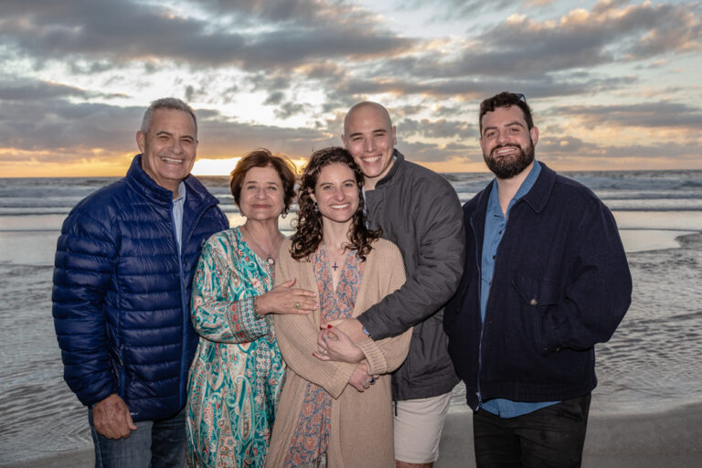 Family standing on the beach at sunset by Katja Photography